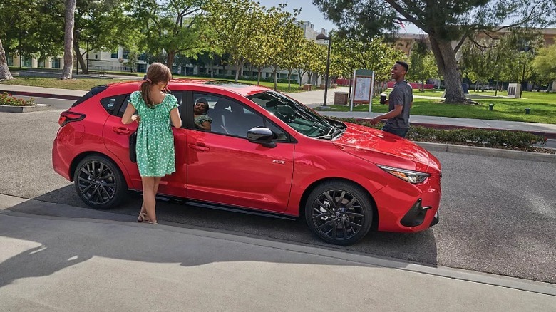 A couple getting into a red Subaru Imprezza