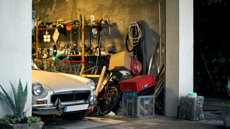 The front end of an MGB poking out of a cluttered garage