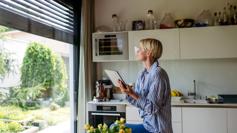 Woman controlling smart blinds using a tablet