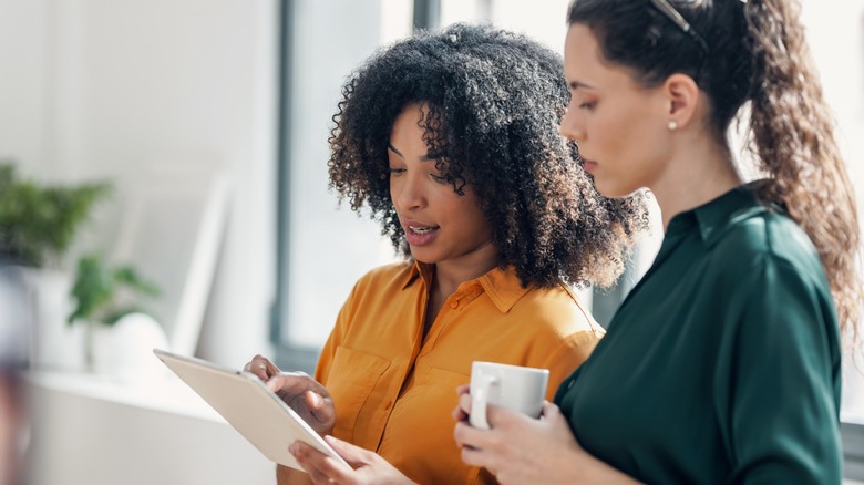 Two womem reading report on a tablet