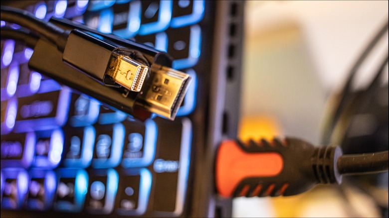 A mini-DP to HDMI adapter cable in front of a laptop with an HDMI cable attached to it.