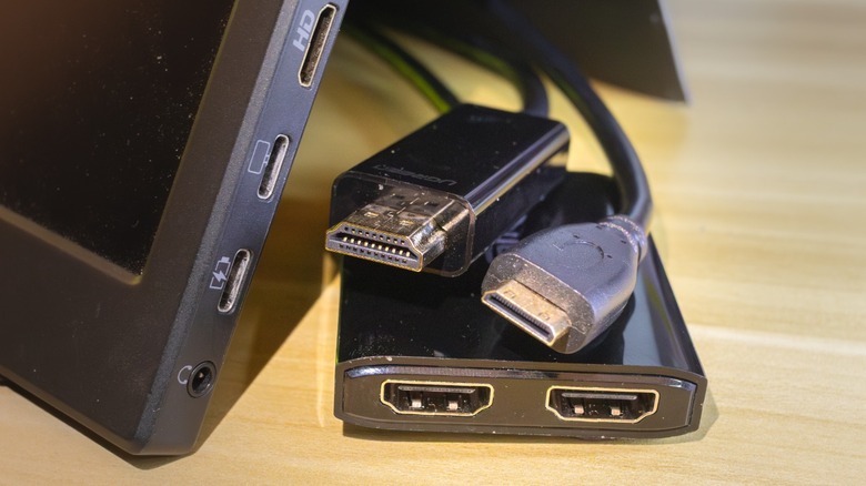 HDMI cable adapters and splitters next to a portable monitor with a mini-HDMI port.