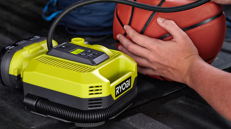 person inflating a basketball
