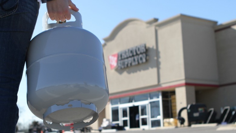 Man carrying a cylinder to a Tractor Supply store.