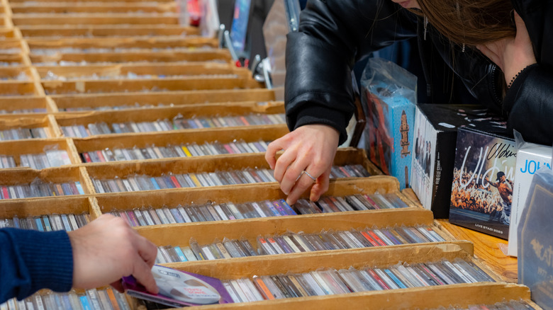 People looking through used CDs in wooden bins
