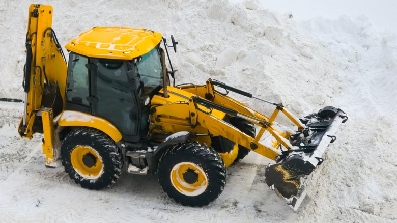 A backhoe loader pushing large snow pile