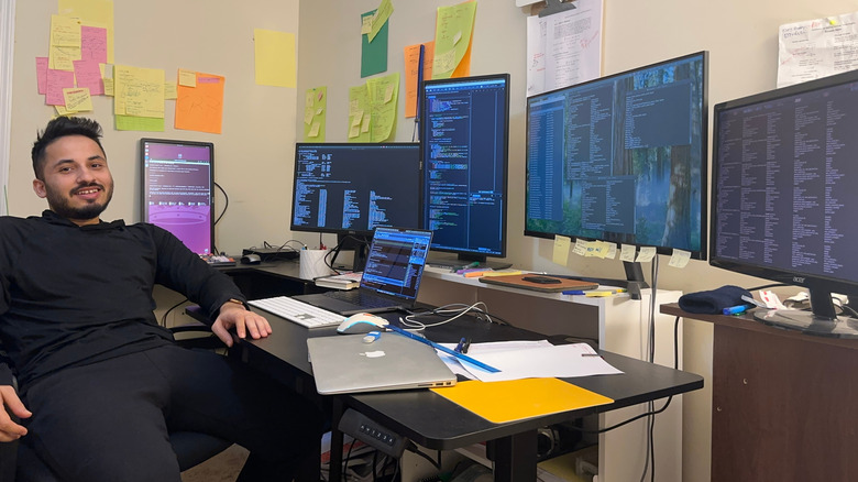 person sitting at desk with multiple monitors