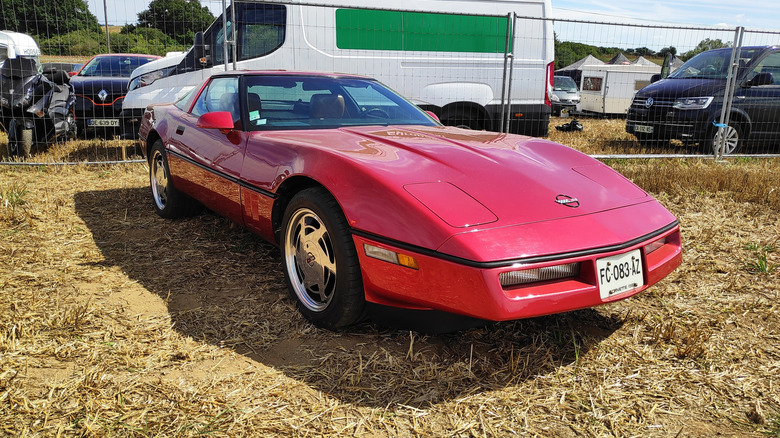 Red C4 Corvette parked in field