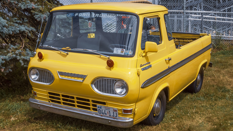 Front 3/4 view of yellow Ford Econoline pickup truck parked at car show.