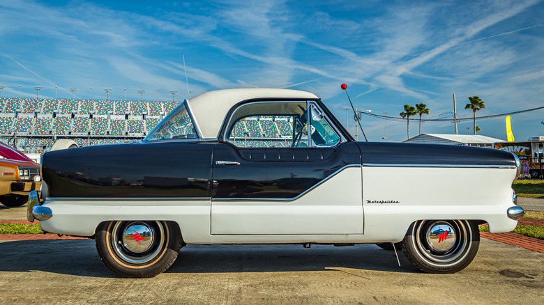 Side view of black and white Nash Metropolitan parked at a car show.