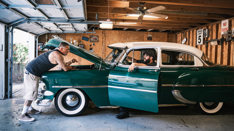 Two people working on a 1953 Chevrolet Bel Air in a garage