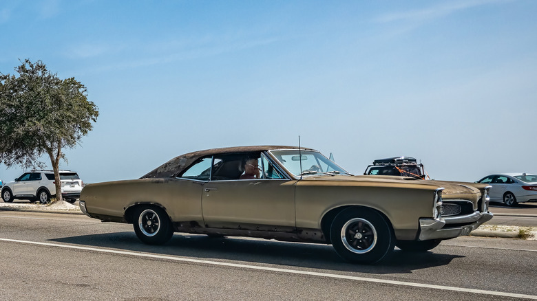 1967 Pontiac GTO driving on modern road.