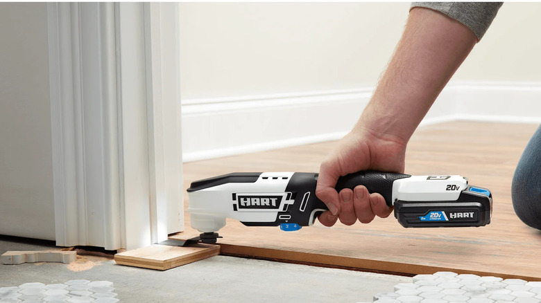 man using oscillating tool on tiles