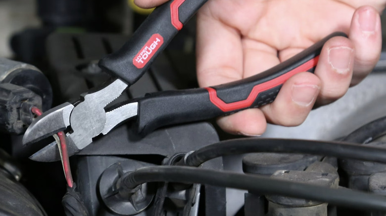 man using pliers to cut wire