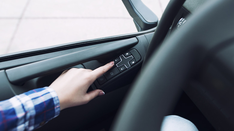 Finger pressing window button in their car