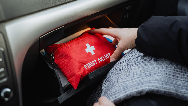 Person putting a first aid kit in glove comparment of car