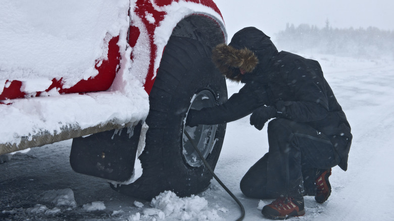 Man inflating tires on a pick up truck in the snow