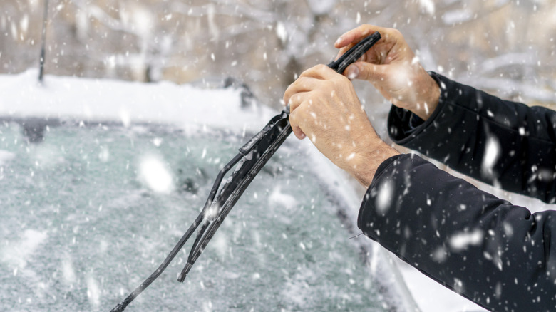 Person checking windshield wipers in snowy weather