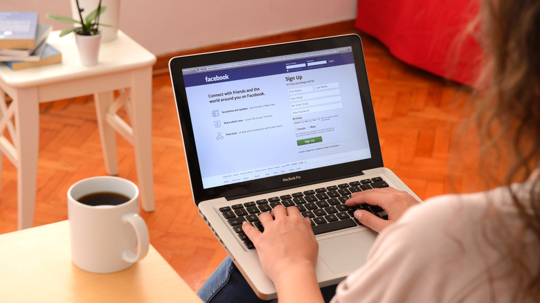 Woman using MacBook Pro displaying Facebook homepage