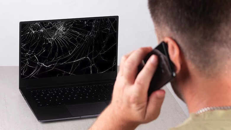 Man on the phone with a broken laptop in front of him