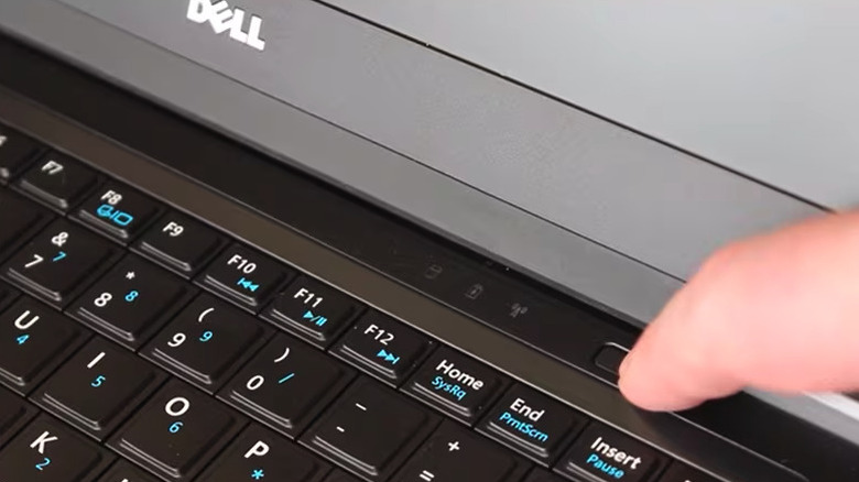 Person preparing to press power button on a laptop
