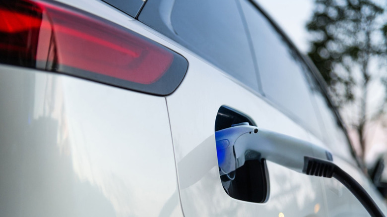 A white car being charged with a plug.