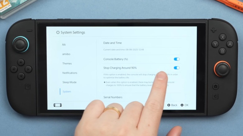 A person pointing at a Nintendo Switch 2's screen to show battery settings.