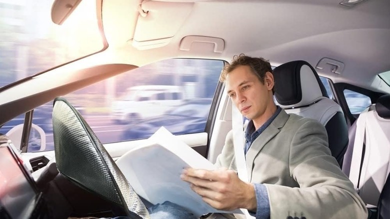 man inside car with steering wheel with cover