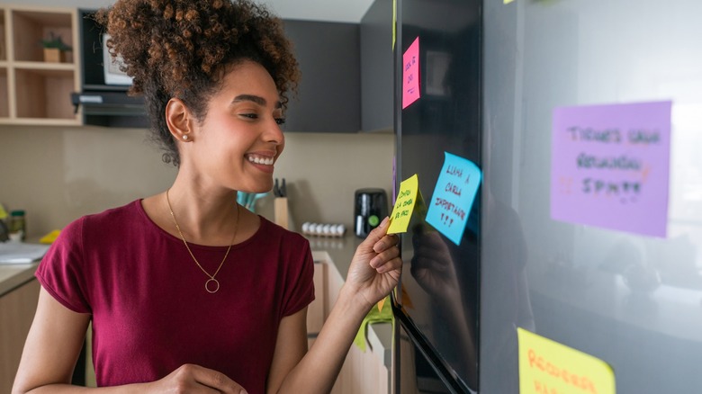 ican American woman at home planning her day using sticky notes 