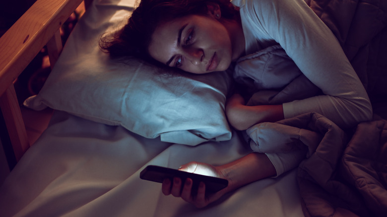 woman using smartphone in bed