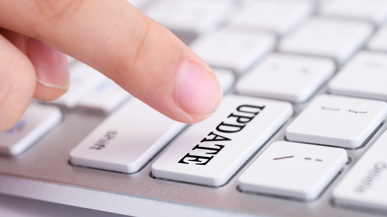 A finger pressing a button called Update on a white keyboard