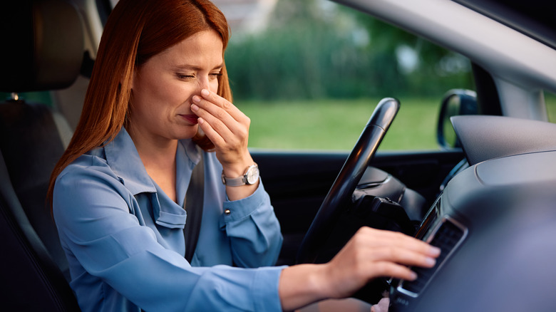 woman in car holding her nose