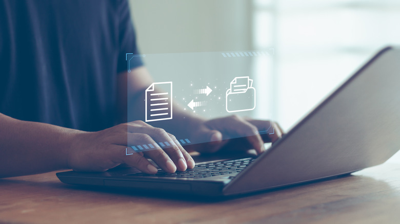 A person typing on a laptop with a file transfer image layered over it