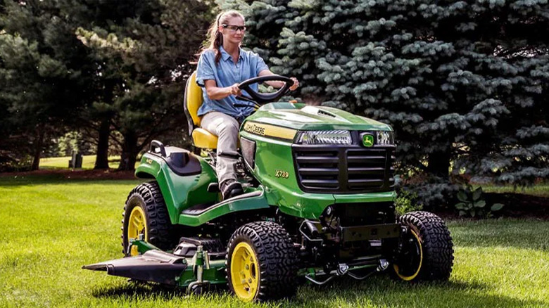A woman riding a John Deere riding tractor