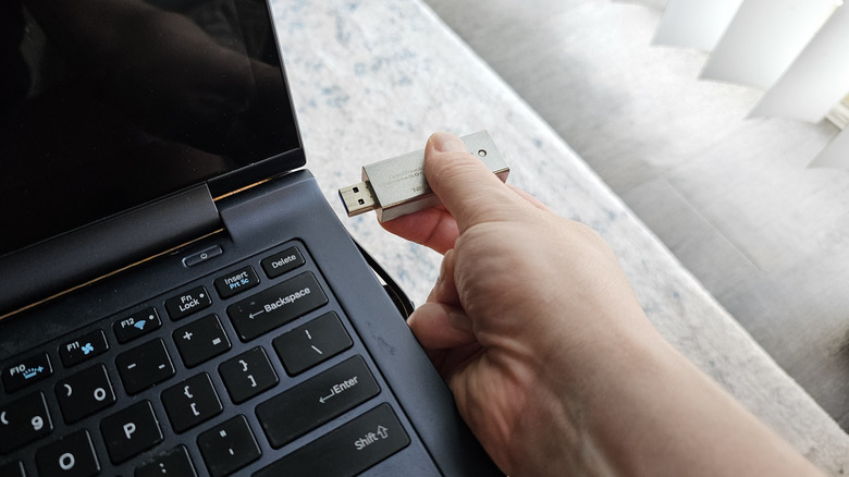 Person inserting USB flash drive into laptop