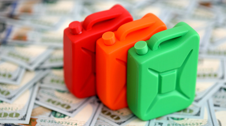 Gasoline canister lies on big amount of dollar bills