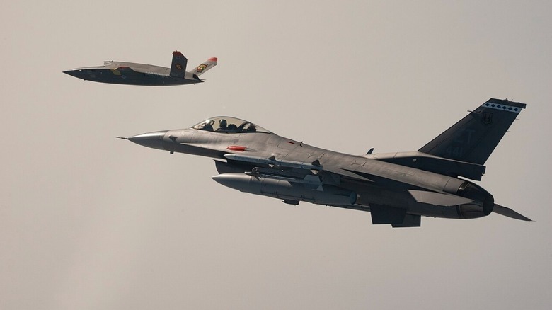 A USMC XQ-58A Valkyrie and USAF F-16 in flight together.