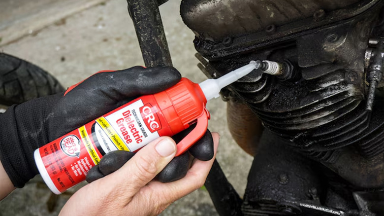 A person adding dielectric grease to a spark plug