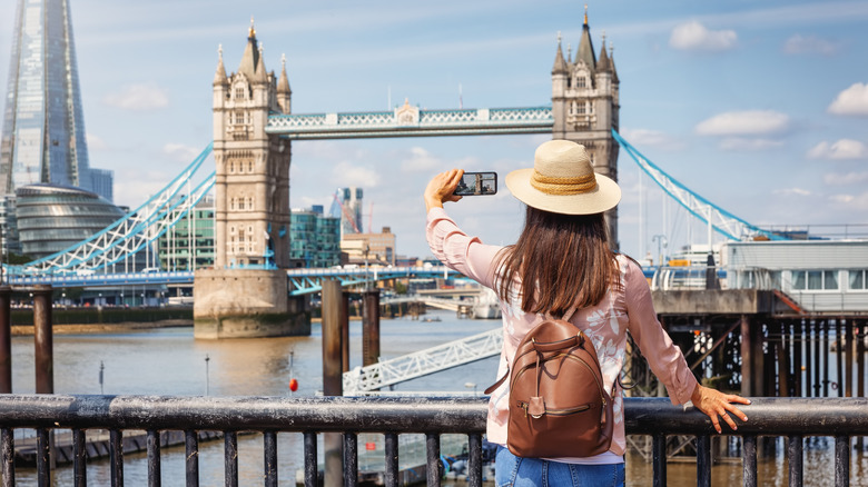 A woman taking photos of the famous Tower Bridge in London, England.