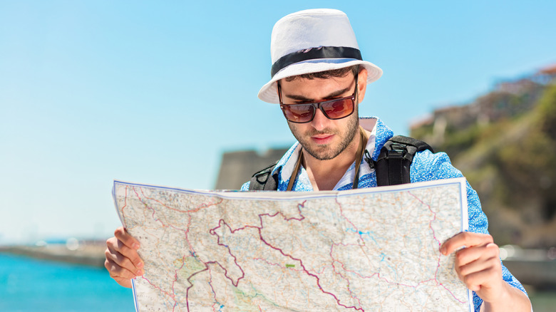 A smiling tourist with map and bag.