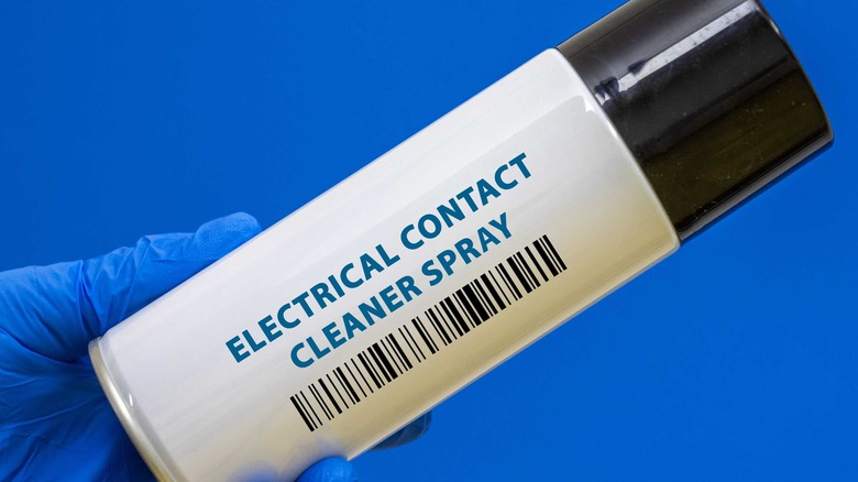 Close-up of hand holding electrical contact cleaner spray tube.