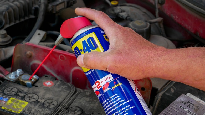 Person using WD-40 spray on car interior.