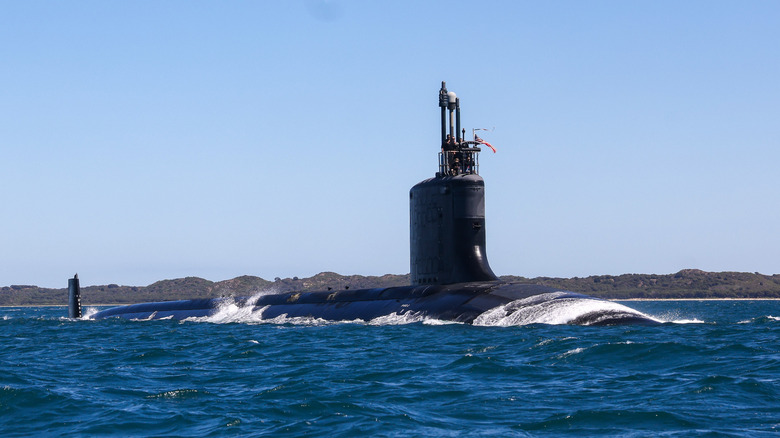 A submarine above water with people and instruments on its conning tower.