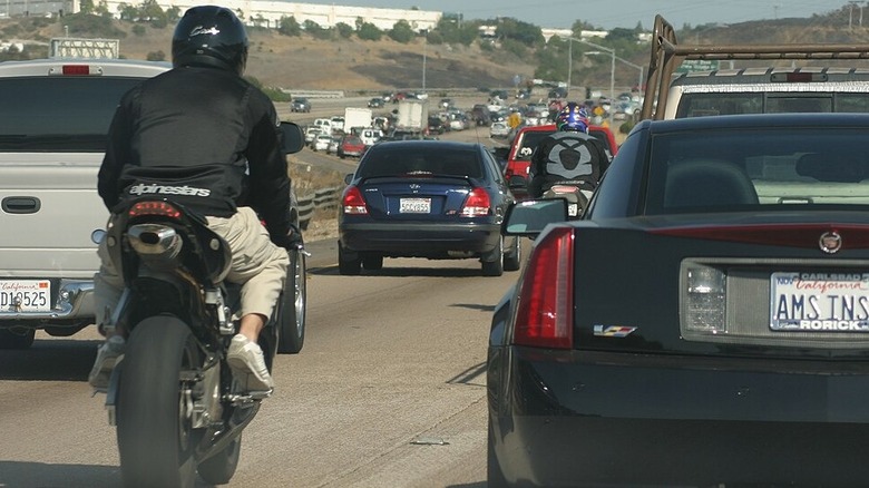 two riders lane splitting on a busy highway