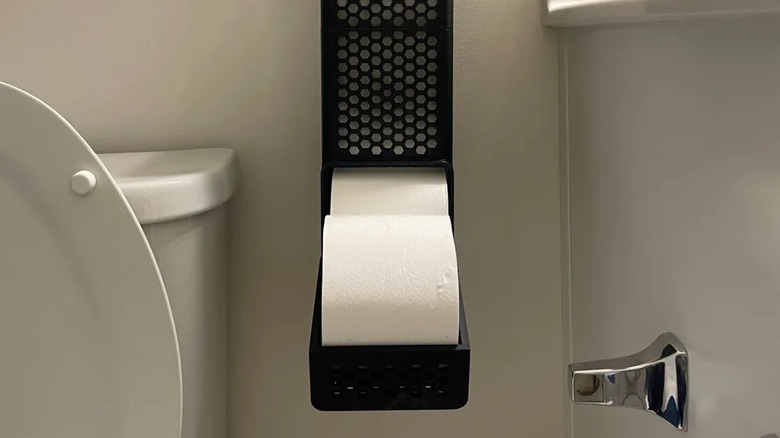 A toilet paper dispenser attached to the wall next to a toilet
