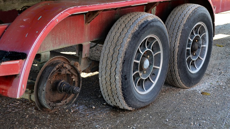 A triple-axle trailer with one wheel missing.