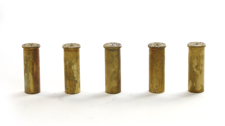 Old brass shells stood up and in a line, white background
