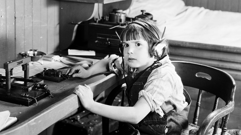 A child sitting at a table with a telegraph machine