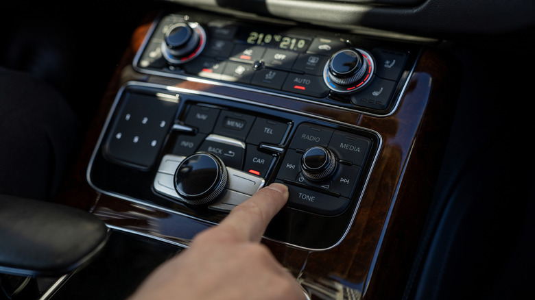 A person using their center console to control the audio playback inside their car