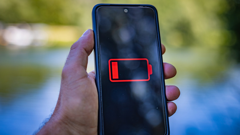 A close up of a handheld Android phone with the low battery indicator on its display